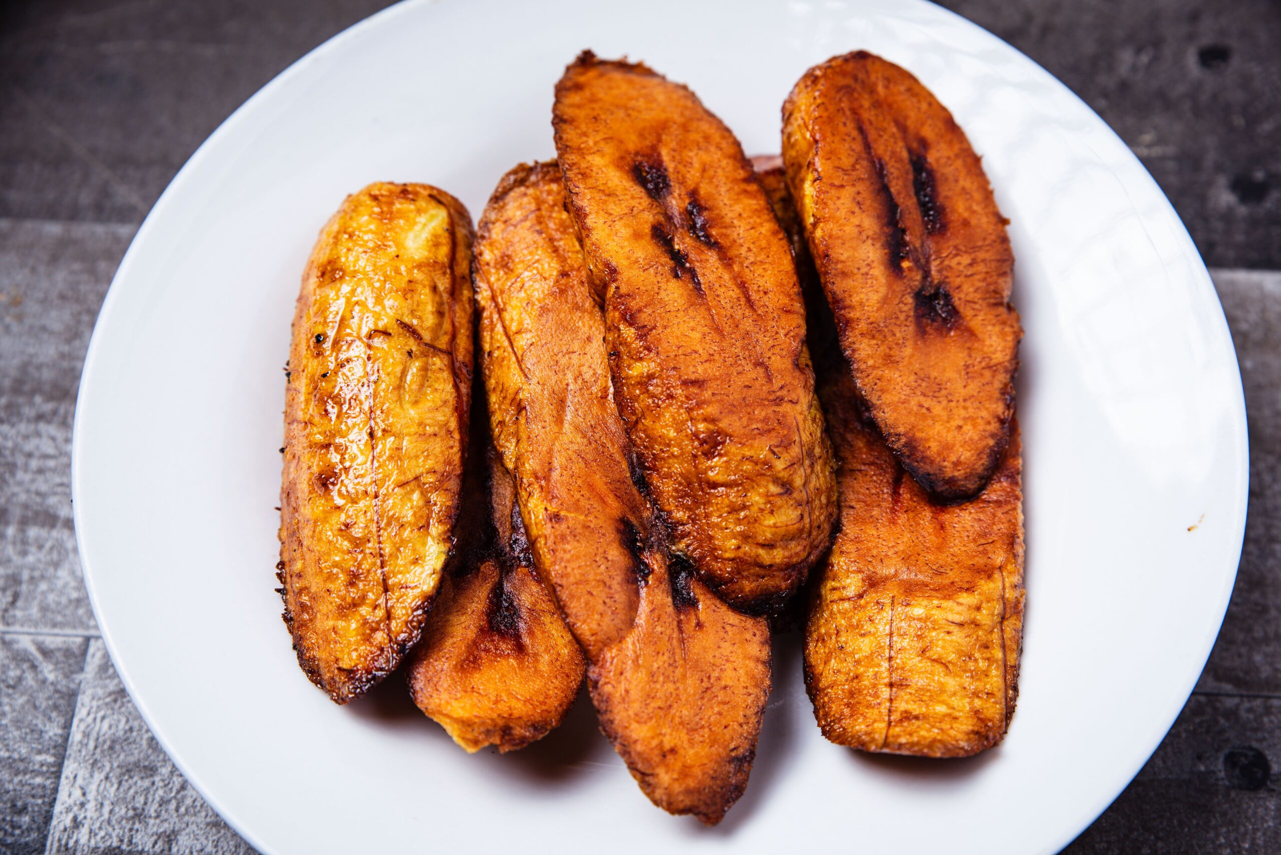 Delicious crispy fried plantains served on a white plate, perfect for a tropical dish.